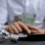 electric light bulb man hands counting expenses b 2025 03 11 17 16 33 utc 1