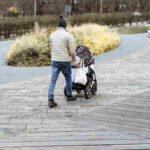 young father walking in park pushing a baby carria 2025 03 08 15 04 55 utc 1