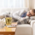 young ill woman lying blanket bed with seasonal illnes drinking hot tea with honey lemon she takes pills cough sirup push disease